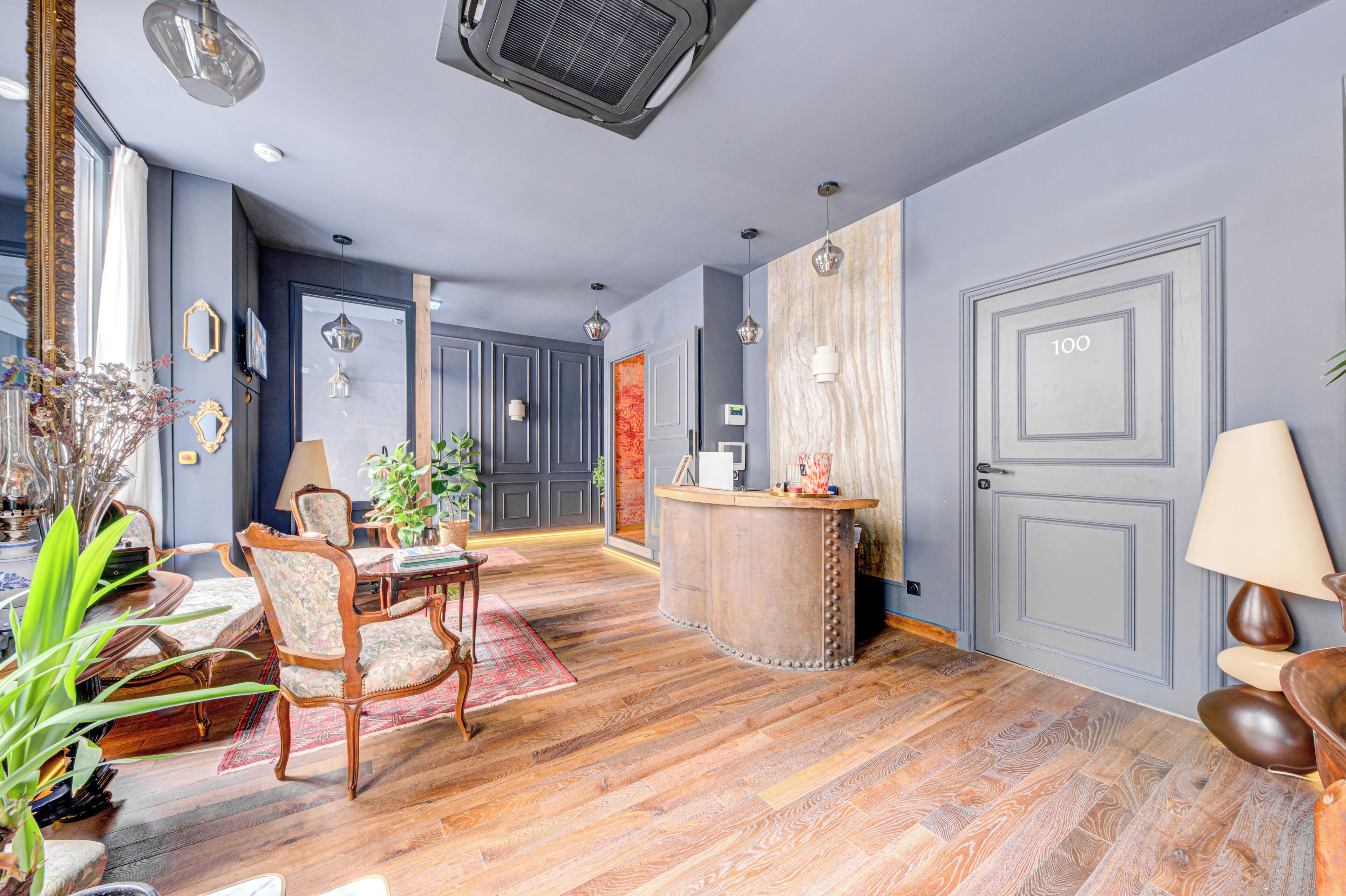 Une pièce dotée d’un plancher en bois, d’un coin repas avec des chaises et une table, d’un bar avec un comptoir et d’un grand miroir.