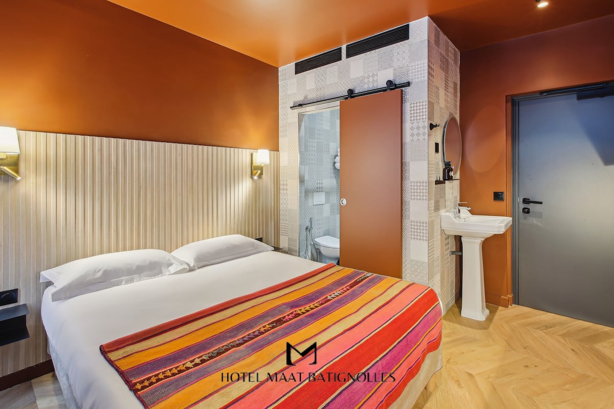 A hotel room with a bed, a bathroom, and a door.
