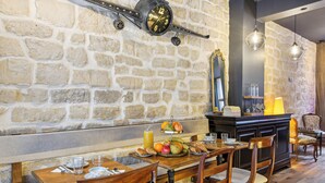 A breakfast setup with a stone wall, wooden furniture, and a clock. - Hôtel Maât Batignolles (Paris)