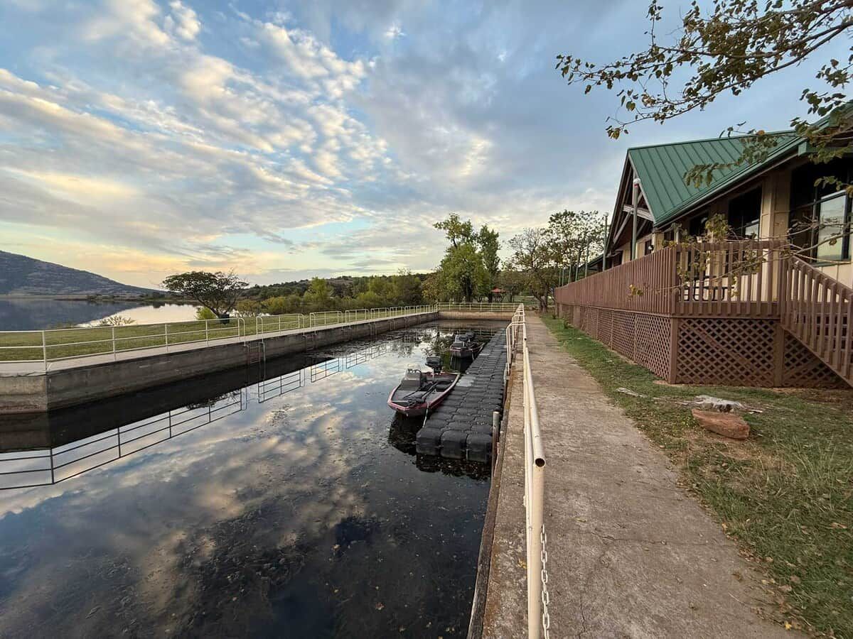 A canal with boats, a wooden building with a green roof, and a clear sky.