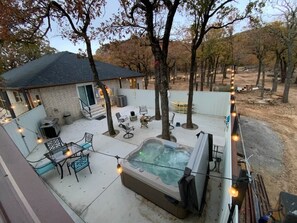 A backyard with a hot tub, outdoor furniture, and string lights.
