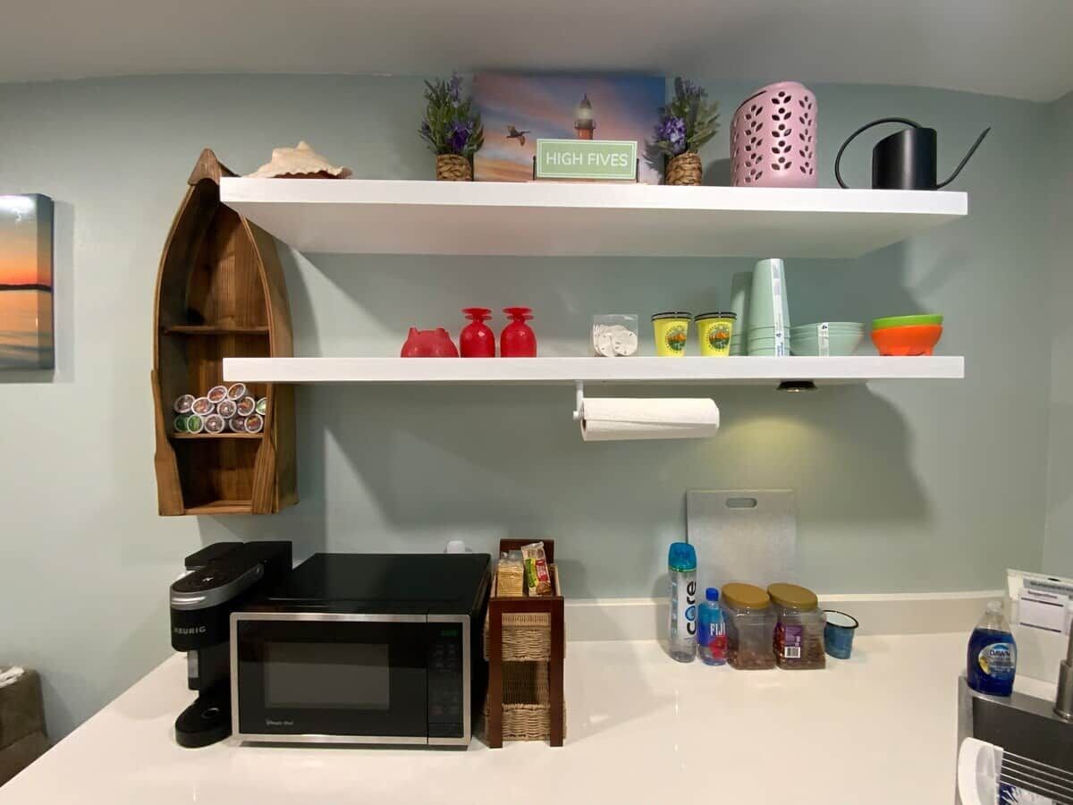 A kitchen with a microwave, a coffee maker, and various kitchen items on shelves.