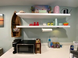 A kitchen with a microwave, a coffee maker, and various kitchen items on shelves.