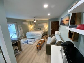 Un dormitorio compacto con cama, mesitas de noche, un escritorio y una silla.