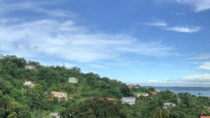 A coastal landscape with houses on a hillside, a body of water, and a clear sky. - Lodges Mont-Vert (Le Robert)