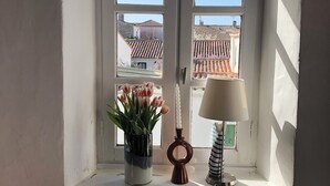 Een kamer met een raam, een vaas met bloemen en een lamp.