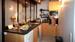 Een kleine keuken met houten kastjes, een magnetron en een spoelbak.