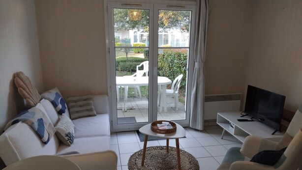 Una sala de estar con sofá, sillones, televisor y mesa de comedor.