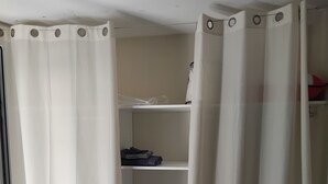 Un dormitorio con cama, armario con estantes y cortina.