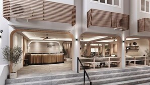 Un hall d’hôtel moderne comprenant un comptoir d’accueil, un espace salon et un escalier menant aux étages supérieurs.