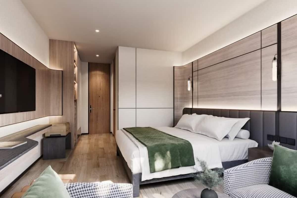 A modern bedroom with a bed, bedside tables, a TV, and a seating area.