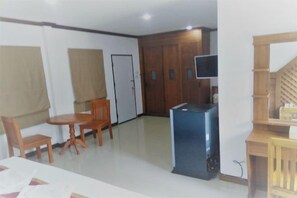Ein Zimmer mit Esstisch, Stühlen, Fernseher und Kleiderschrank.