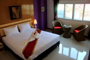 Une chambre d’hôtel avec un lit, une chaise, une petite table et une fenêtre.