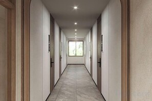 Un couloir avec des portes de chaque côté, un éclairage encastré et une vue sur l’extérieur.
