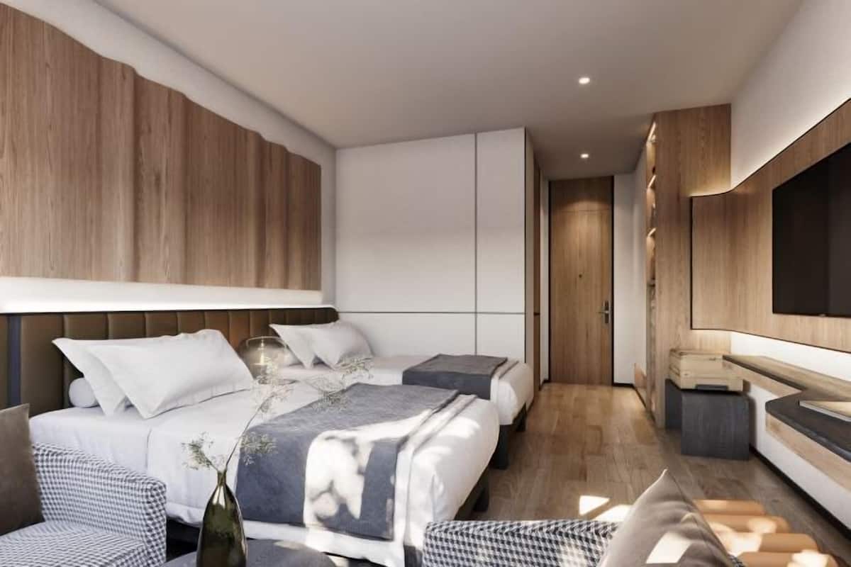 A modern hotel room with a large bed, a TV, and a wooden accent wall.