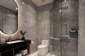 A modern bathroom with a marble sink, toilet, and glass shower enclosure. - Panmanee Hotel-Newly Renovated (Phi Phi Islands)