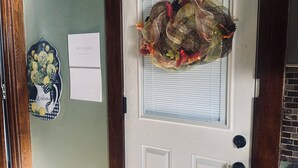 Una porta con un'ghirlanda decorativa, un cartello di benvenuto e un calendario appeso al muro.
