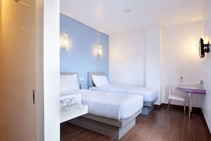 Habitación de hotel con dos camas, un escritorio pequeño y un baño.
