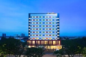 Un hôtel à plusieurs étages, doté d’un design moderne, avec une série de fenêtres et une entrée imposante.