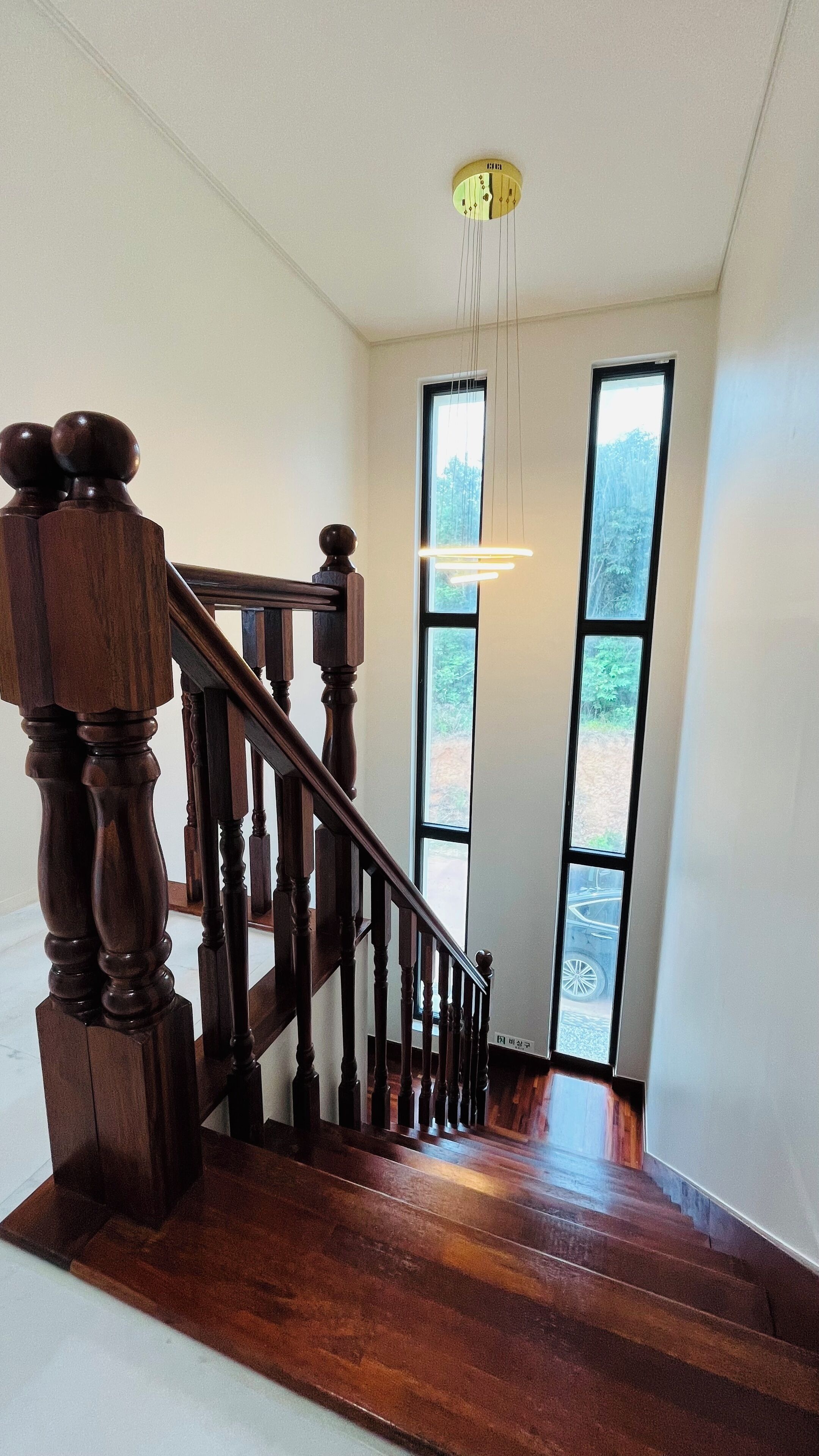 A wooden staircase with a handrail and a light fixture above.