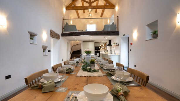 A dining area with a wooden table set for a meal, surrounded by chairs. - Luxury farm cottage in the beautiful Peak District (Eyam)