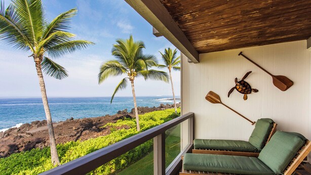 A balcony with a view of the ocean, palm trees, and a wooden ceiling. - Exquisite Oceanfront Beautifully Upgraded Corner Unit - Vrkcv (Kailua-Kona)