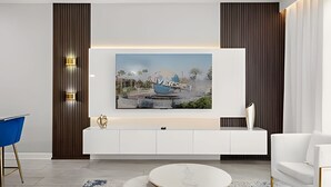 A modern living room with a white entertainment unit, a round coffee table, and a blue chair. - 4BR w/ Mickey & Mario Rooms + Heated Pool (Davenport)