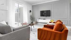 Una sala de estar moderna con un sofá, una mesa de centro y un televisor montado en la pared.