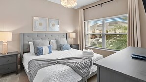 Une chambre moderne avec un grand lit, des tables de chevet, un bureau et un lustre.