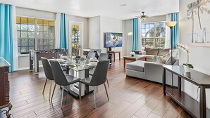 A spacious living area with a dining table, sofas, and a TV. - Vista Cay 4BR Condo w/ Balcony & Foosball Fun (Orlando)