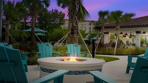 A circular outdoor seating area with a fire pit, surrounded by turquoise chairs and a tiled border. - Vista Cay 4BR Condo w/ Balcony & Foosball Fun (Orlando)