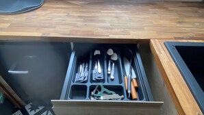 A kitchen with a drawer organizer containing utensils and a window above it. - Pleasant apartment in the heart of the city (Orléans)