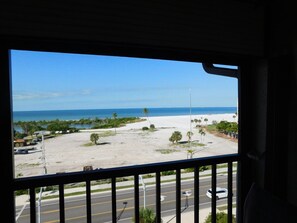 A view from a window overlooking a beach with a road in the foreground. - Estero Cove Gulf View 2/2 Condo (Fort Myers Beach)