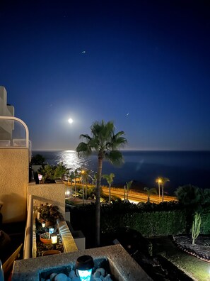 A night view of a coastal area with a clear sky, a visible moon, and a road with streetlights. - ‘Mijas’ Apartment with Large Seafront Terrace, Wi-Fi & Air Conditioning (Málaga)