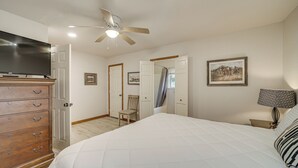 Une chambre à coucher comprenant un lit, une commode, un ventilateur de plafond et un téléviseur.