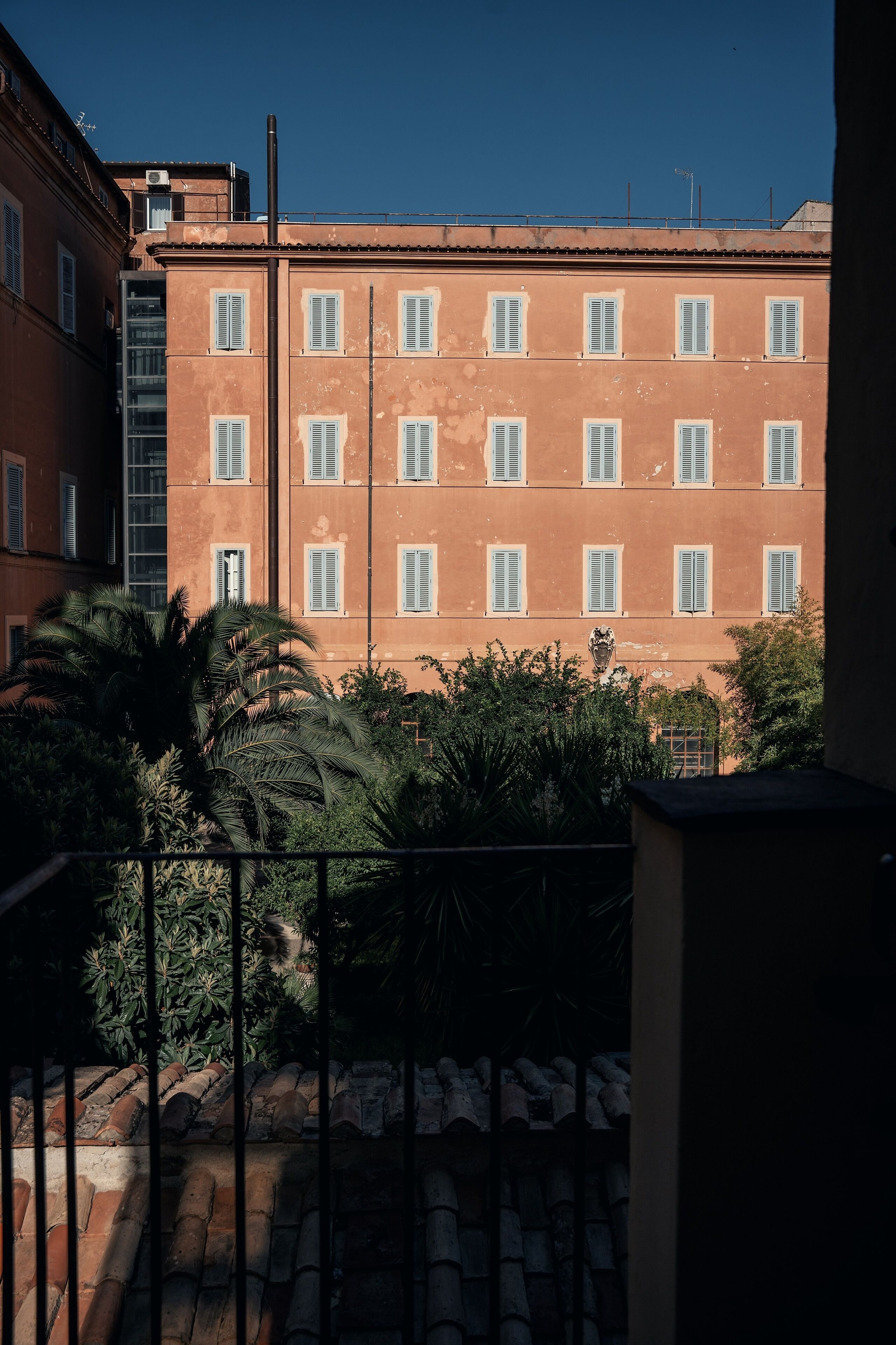 A multi-story building with evenly spaced windows and a balcony area with a metal railing.
