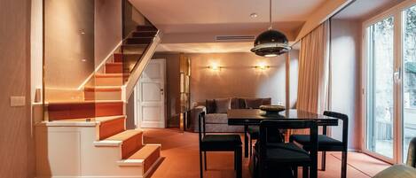 A modern interior with a staircase, dining area, and large windows.