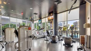 A gym with cardio machines, weight stations, and a large window offering a city view. - Large 2-Bedroom Condo Near Ocean w Amenities 1009 (Hallandale Beach)