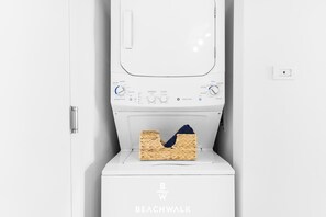 Une machine à laver blanche, avec un panier de linge et une serviette posée sur le dessus.
