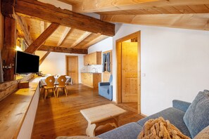 Interior em madeira com televisão, móveis de madeira, sofá e área de cozinha.