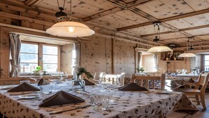 A dining area with wooden walls, tables set with tablecloths, and hanging pendant lights. - Apartment 'Plazores Dai Nüsc' with Mountain View, Shared Terrace and Wi-Fi (St. Vigil)