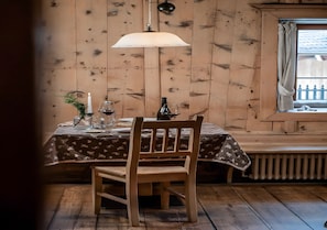 Een houten eettafel met een kaars, een glas en een fles.