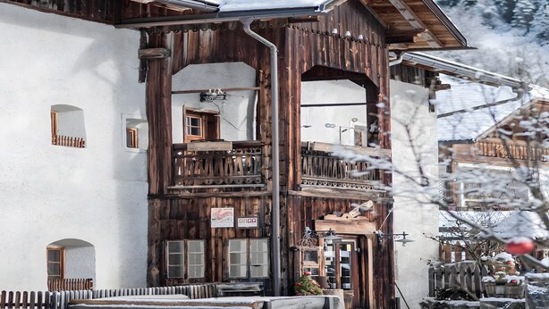 Un edificio de madera con un balcón, un letrero y una ventana.