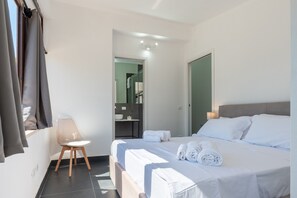 A hotel room with a bed, a chair, a bathroom visible through an open door, and a window with curtains. - Room 'Altavilla 1' with Shared Garden and Air Conditioning (Altavilla Milicia)