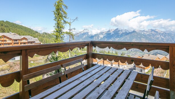 Una terraza de madera con un banco que da a un paisaje montañoso.