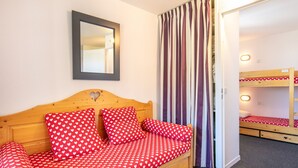 Una cama individual con una colcha estampada con motivos de corazones, un cabecero de madera y un espejo encima.