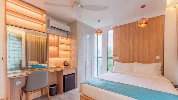 A modern bedroom with a large bed, a desk with a chair, and a mirror. - Star Shell (Hulhumale)