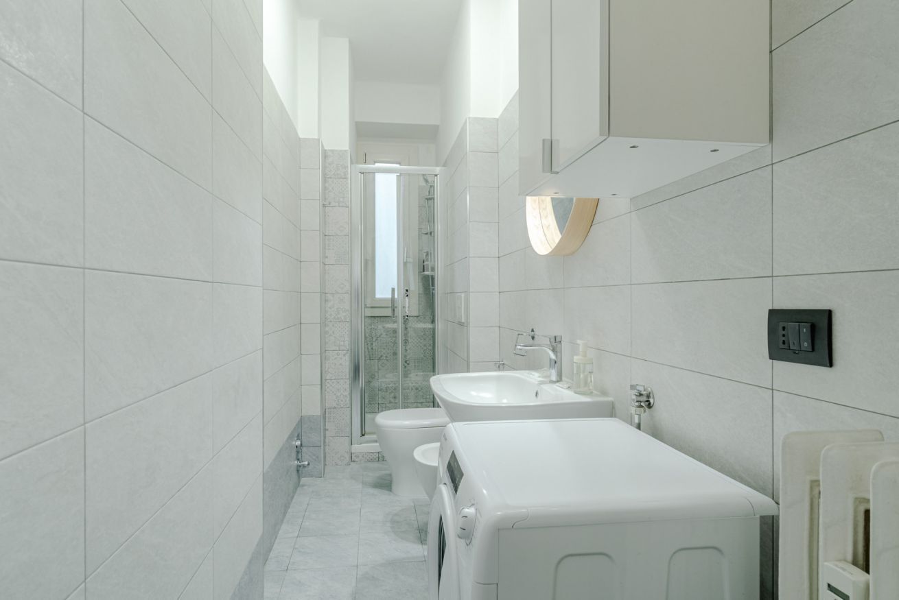 Un bagno moderno con doccia, WC e lavatrice integrata.