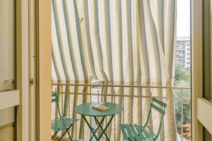 A balcony with striped curtains, a small table, and two chairs. - GuestHost - A comfortable and welcoming 68 square meters apartment, perfect for four people, located on the first floor of a building (NO elevator).The property is located in the lively Borgo San Paolo neighborhood and is well connected to the city cente (Turin)