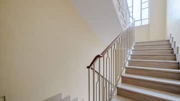 A staircase with a wooden handrail and metal balusters, leading to a landing with a window.